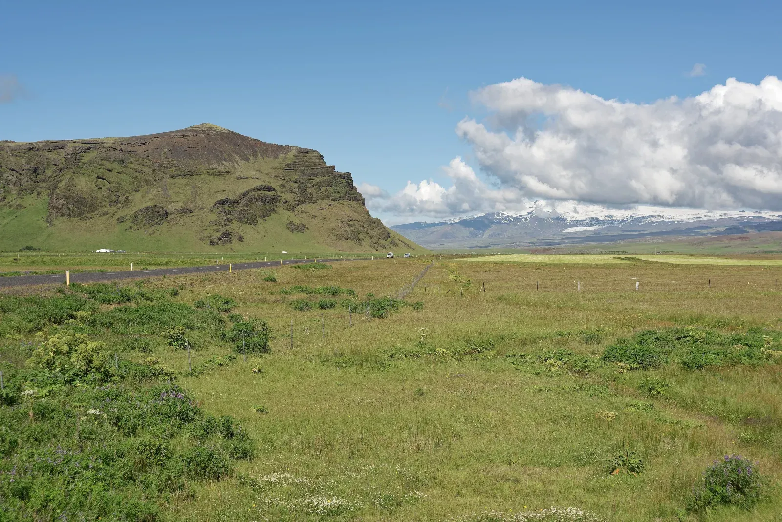 A paved road crossing a dark volcanic landscape in southern Iceland
